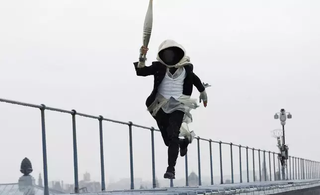 A torch bearer runs atop the Musee d'Orsay, in Paris, France, during the opening ceremony of the 2024 Summer Olympics, Friday, July 26, 2024. (Peter Cziborra/Pool Photo via AP)