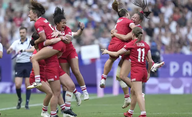 Members of the Canadian team celebrate after winning the women's semifinal Rugby Sevens match between Canada and Australia at the 2024 Summer Olympics, in the Stade de France, in Saint-Denis, France, Tuesday, July 30, 2024. Canada won the game 21-12. (AP Photo/Tsvangirayi Mukwazhi)