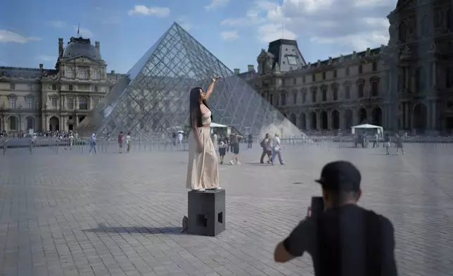 A woman from Mexico poses in the courtyard of the Louvre museum, which is outside the security perimeter set up for the Olympic Games, Friday, July 19, 2024, in Paris, France. (AP Photo/David Goldman)