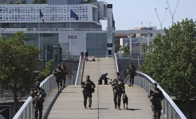 Soldiers patrol on a footbridge over the Seine river ,Wednesday, July 17, 2024 in Paris. France's armed forces held a demonstration of the security measures planned on the River Seine, both in and out of the water, to make it safe for athletes and spectators during the opening ceremony of the Paris Olympics. Organizers have planned a parade of about 10,000 athletes through the heart of the French capital on boats on the Seine along a 6-kilometer (3.7-mile) route at sunset on July 26. (AP Photo/Aurelien Morissard)