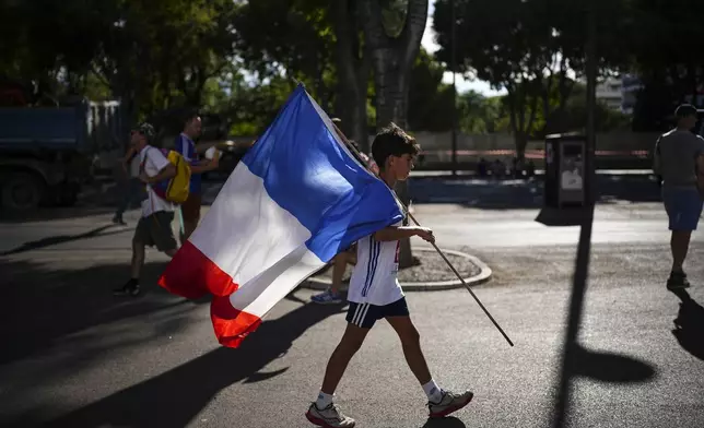 11-year-old Guillaume Valot from Toulon walks with a French flag before the start of the men's Group A soccer match between France and the United States at the Velodrome stadium, during the 2024 Summer Olympics, Wednesday, July 24, 2024, in Marseille, France. (AP Photo/Daniel Cole)