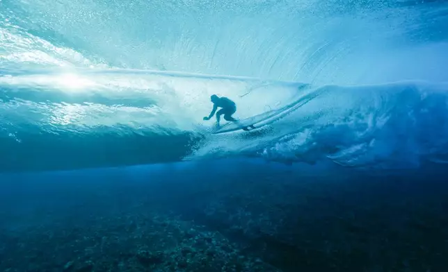 France's Joan Duru rides in a barrel in the 2nd heat, during round one of the surfing competition, during the 2024 Summer Olympics, in Teahupo'o, French Polynesia, Saturday, July 27, 2024. (Ben Thouard/Pool Photo via AP)