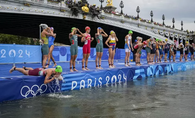 Hungary's Zsanett Kuttor-Bragmayer, left, splashes water on her face before the start of the women's individual triathlon competition at the 2024 Summer Olympics, Wednesday, July 31, 2024, in Paris, France. (AP Photo/Vadim Ghirda)