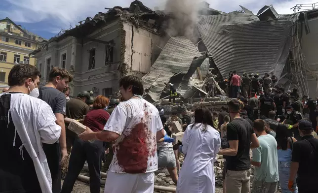 Rescuers, volunteers and medical workers, some in bloodied uniforms clean up the rubble and search victims after Russian missile hit the country's main children hospital Okhmadit, in Kyiv, Ukraine, Monday, July 8, 2024. A major Russian missile attack across Ukraine killed at least 20 people and injured more than 50 on Monday, officials said, with one missile striking a large children’s hospital in the capital, Kyiv, where emergency crews searched rubble for casualties. (AP Photo/Efrem Lukatsky)