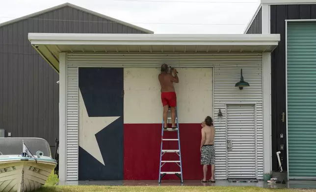 Clyde George, left, and his son Chris George board up their home ahead of the arrival of Tropical Storm Beryl on Sunday, July 7, 2024, in Port O'Connor, Texas. (Jon Shapley/Houston Chronicle via AP)