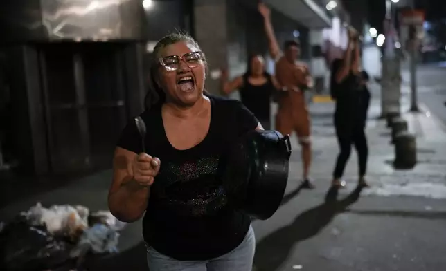 Supporters of opposition candidate Edmundo Gonzalez bang pots after the polls closed for the presidential election in Caracas, Venezuela, Sunday, July 28, 2024. (AP Photo/Matias Delacroix)