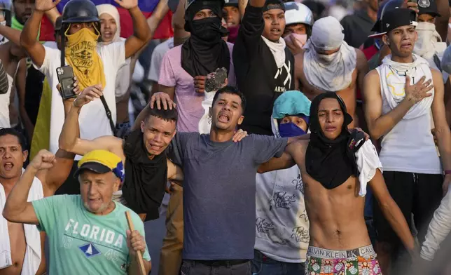 Protesters embrace while singing Venezuela's national anthem during demonstrations against the official election results declaring President Nicolas Maduro's reelection, the day after the vote in Caracas, Venezuela, Monday, July 29, 2024. (AP Photo/Matias Delacroix)