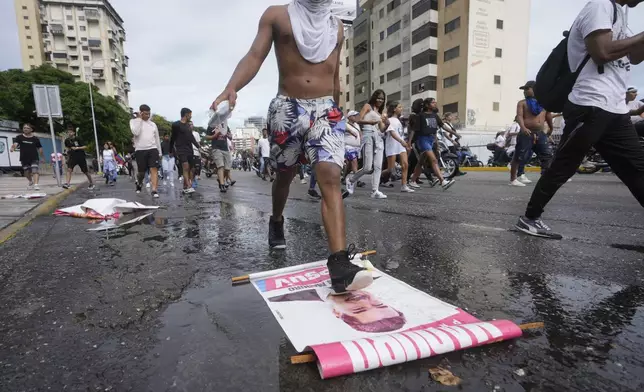 A protester steps on a campaign sign of President Nicolas Maduro during a march against hish being declared the winner of the presidential election, the day after the vote in Caracas, Venezuela, Monday, July 29, 2024. (AP Photo/Fernando Vergara)