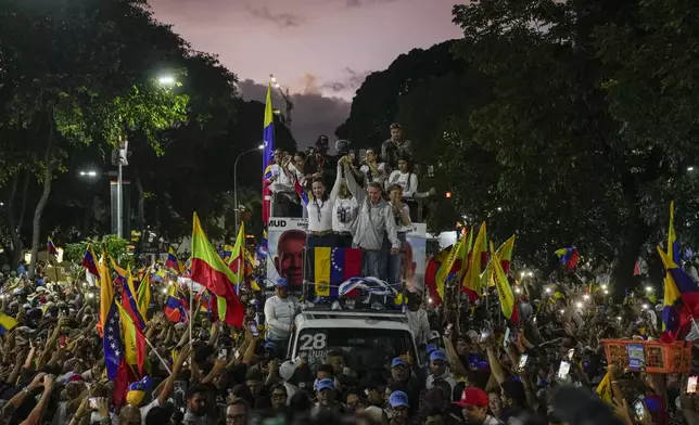 Opposition leader Maria Corina Machado, center left, and presidential candidate Edmundo Gonzalez raise their arms during their closing campaign rally in Caracas, Venezuela, Thursday, July 25, 2024. The presidential election is set for July 28. (AP Photo/Matias Delacroix)