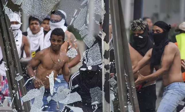 Protesters smash an advertising board during demonstrations against the official election results declaring President Nicolas Maduro's reelection, the day after the vote in Caracas, Venezuela, Monday, July 29, 2024. (AP Photo/Matias Delacroix)