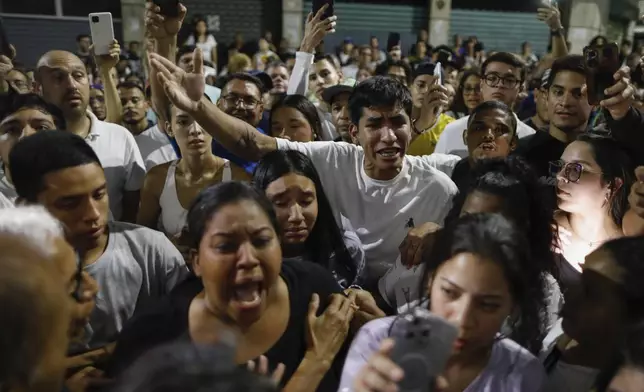 Supporters of opposition candidate Edmundo Gonzalez gather outside the Andres Bello School voting center, asking for the results, after the polls closed for the presidential elections in Caracas, Venezuela, Sunday, July 28, 2024. (AP Photo/Cristian Hernandez)