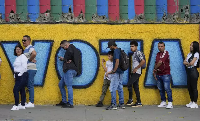 Voters line up outside a polling station that reads in Spanish "Vote" during the presidential election in Caracas, Venezuela, Sunday, July 28, 2024. (AP Photo/Fernando Vergara)