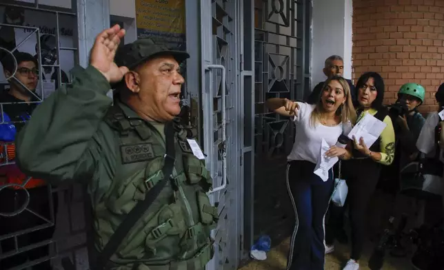 A National Guard officer addresses voters lining up at the Andres Bello School as opposition poll watchers argue they are not being allowed to enter the voting center during the presidential elections in Caracas, Venezuela, Sunday, July 28, 2024. (AP Photo/Cristian Hernandez)