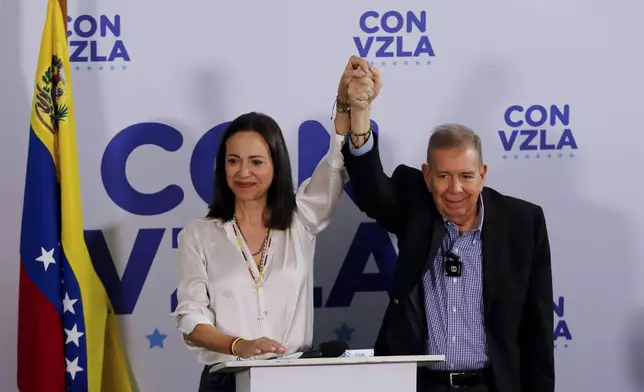 Opposition presidential candidate Edmundo Gonzalez, right, and opposition leader Maria Corina Machado join hands during a press conference the day after the election in Caracas, Venezuela, Monday, July 29, 2024. (AP Photo/Cristian Hernandez)