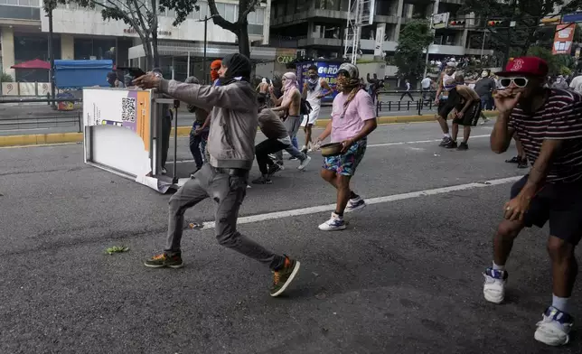 A protester aims a weapon during clashes with police amid demonstrations against the official election results declaring President Nicolas Maduro's reelection in Caracas, Venezuela, Monday, July 29, 2024, the day after the vote. (AP Photo/Fernando Vergara)