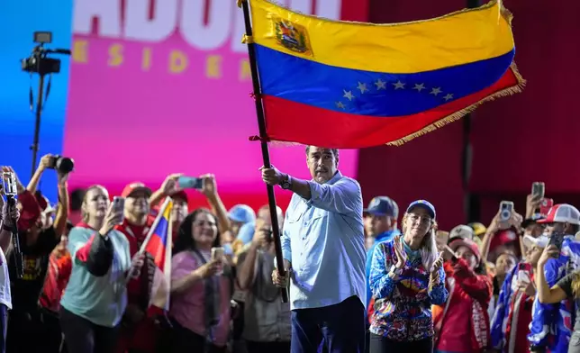 President Nicolas Maduro waves a Venezuelan flag during his closing election campaign rally in Caracas, Venezuela, Thursday, July 25, 2024. Maduro is seeking re-election for a third term in the July 28 vote. (AP Photo/Fernando Vergara)