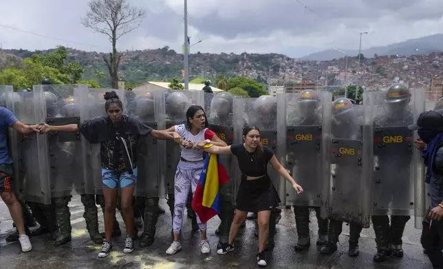 Residents try to block a street to protest the official results the day after the presidential election as National Guards work to remove them in Caracas, Venezuela, Monday, July 29, 2024. (AP Photo/Fernando Vergara)