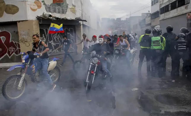 Protesters demonstrating against the official election results declaring President Nicolas Maduro's reelection ride through tear gas fired by police the day after the vote in Caracas, Venezuela, Monday, July 29, 2024. (AP Photo/Cristian Hernandez)