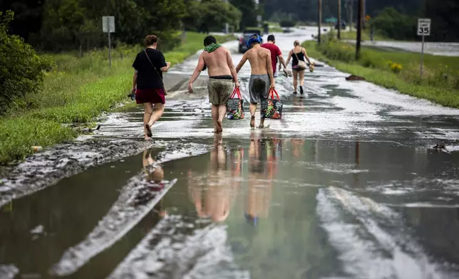 Residents walk barefoot away from flood damage in Lyndon, Vt., Tuesday, July 30, 2024. (AP Photo/Dmitry Belyakov)