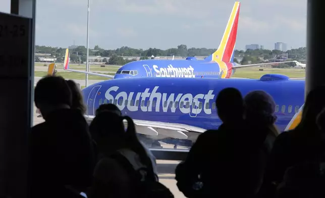 Southwest passengers and airliners line up and move at Love Field in Dallas, Thursday, July 25, 2024. Southwest Airlines said Thursday that it plans to drop the open-boarding system it has used for more than 50 years and will start assigning passengers to seats, just like all the other big airlines. (AP Photo/LM Otero)