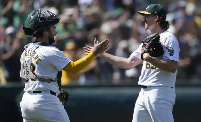 Oakland Athletics catcher Shea Langeliers, left, celebrates with pitcher Tyler Ferguson, right, after they defeated the Los Angeles Angels in a baseball game in Oakland, Calif., Saturday, July 20, 2024. (AP Photo/Jeff Chiu)