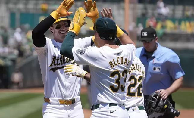 Oakland Athletics' Brent Rooker, left, celebrates after hitting a three-run home run that also scored JJ Bleday (33) and Miguel Andujar (22) during the first inning of a baseball game against the Los Angeles Angels in Oakland, Calif., Saturday, July 20, 2024. (AP Photo/Jeff Chiu)