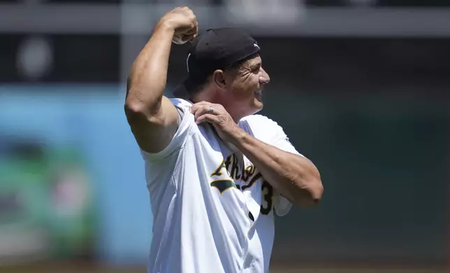 Former Oakland Athletics player Jose Canseco flexes for fans before throwing out a ceremonial first pitch before a baseball game between the Athletics and the Los Angeles Angels in Oakland, Calif., Saturday, July 20, 2024. (AP Photo/Jeff Chiu)