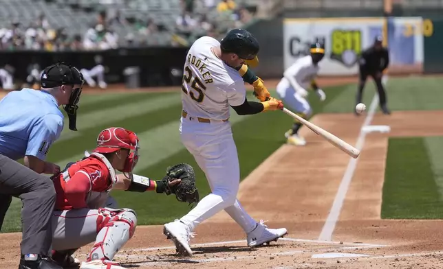 Oakland Athletics' Brent Rooker (25) hits a three-run home run in front of Los Angeles Angels catcher Logan O'Hoppe, second from left, during the first inning of a baseball game in Oakland, Calif., Saturday, July 20, 2024. (AP Photo/Jeff Chiu)