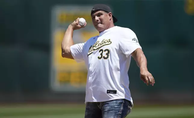 Former Oakland Athletics player Jose Canseco throws out a ceremonial first pitch before a baseball game between the Athletics and the Los Angeles Angels in Oakland, Calif., Saturday, July 20, 2024. (AP Photo/Jeff Chiu)