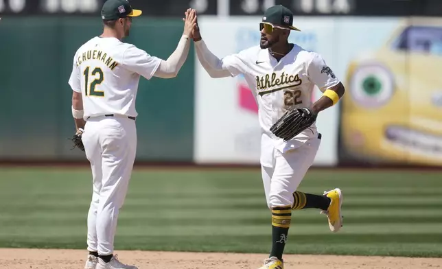 Oakland Athletics ' Max Schuemann (12) celebrates with Miguel Andujar (22) after they defeated the Los Angeles Angels in a baseball game in Oakland, Calif., Saturday, July 20, 2024. (AP Photo/Jeff Chiu)