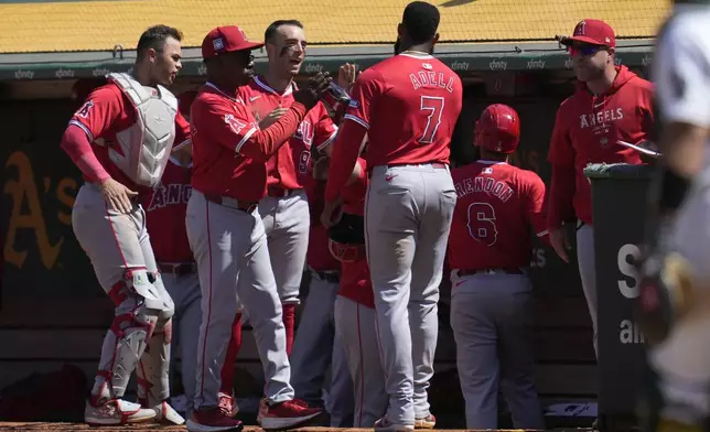 Los Angeles Angels' Jo Adell (7) is congratulated by manager Ron Washington, second from left, and teammates after scoring during the eighth inning of a baseball game against the Oakland Athletics in Oakland, Calif., Sunday, July 21, 2024. (AP Photo/Jeff Chiu)