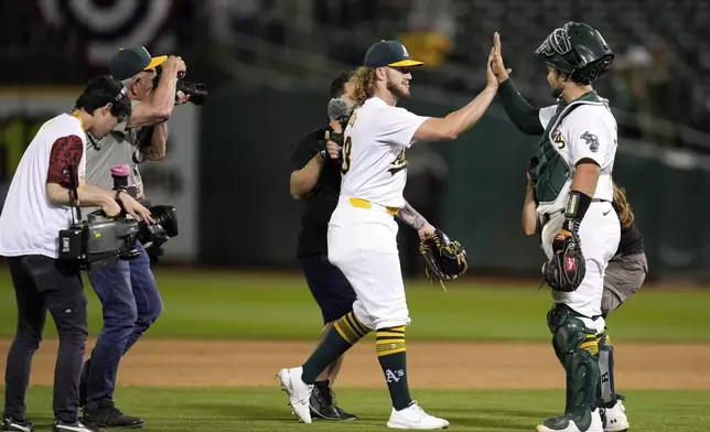 Oakland Athletics pitcher Joey Estes, center, celebrates with catcher Shea Langeliers, right, after the team's victory over the Los Angeles Angels in a baseball game Wednesday, July 3, 2024, in Oakland, Calif. (AP Photo/Godofredo A. Vásquez)