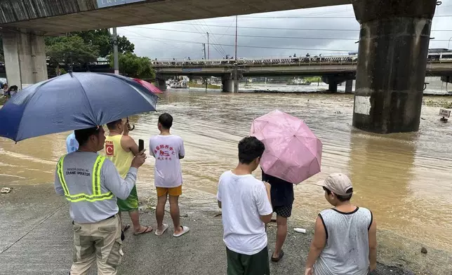 Residents watch the Marikina river as it floods from monsoon rains worsened by offshore typhoon Gaemi on Wednesday, July 24, 2024, near Manila, Philippines. (AP Photo/Joeal Capulitan)