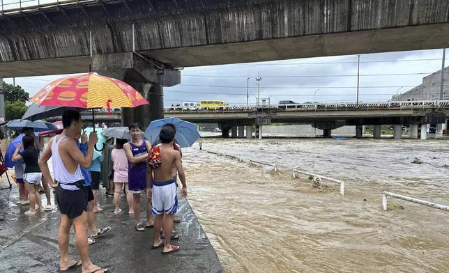 Residents watch the Marikina river as it floods from monsoon rains worsened by offshore typhoon Gaemi on Wednesday, July 24, 2024, near Manila, Philippines. (AP Photo/Joeal Capulitan)