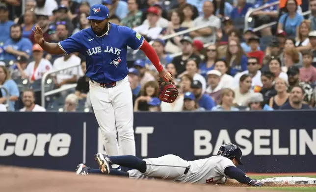 Houston Astros' Jose Altuve (27) dives safely into first base as Toronto Blue Jays first baseman Vladimir Guerrero Jr. (27) looks during the first inning of a baseball game, Tuesday, July 2, 2024, in Toronto. (Jon Blacker/The Canadian Press via AP)