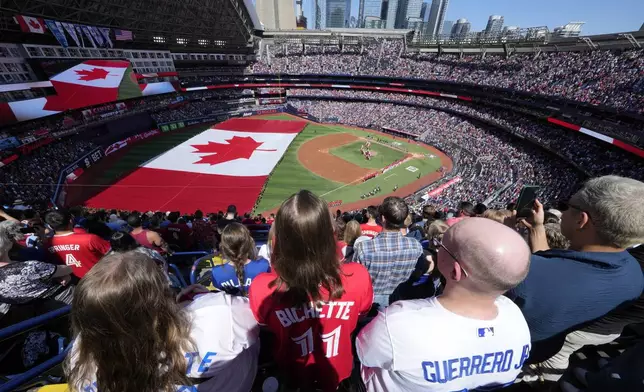 Fans look on as a huge Canadian flag is unfurled before the start of a baseball game between the Houston Astros and Toronto Blue Jays in Toronto, Monday, July 1, 2024. (Frank Gunn/The Canadian Press via AP)