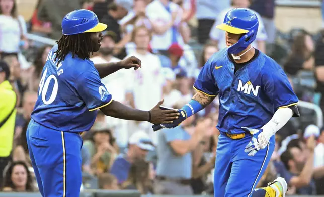 Minnesota Twins' Jose Miranda, right, celebrates with third base coach Tommy Watkins, left, after hitting a home run off Houston Astros starting pitcher Shawn Dubin during the third inning of a baseball game Friday, July 5, 2024, in Minneapolis. (AP Photo/Craig Lassig)