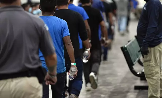 FILE - A group of men are escorted in a Border Patrol processing center, Friday, Dec. 15, 2023, in Tucson, Ariz. (AP Photo/Gregory Bull, File)