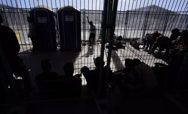 FILE - Men wait in a holding area Friday, Dec. 15, 2023, at a Border Patrol station in Ajo, Ariz. (AP Photo/Gregory Bull,File)