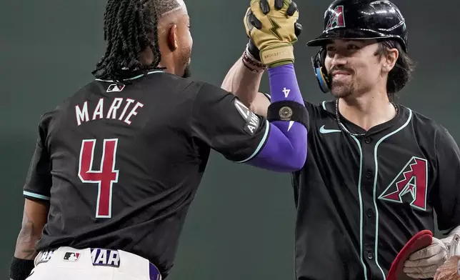 During a pitching change, Arizona Diamondbacks' Ketel Marte (4) congratulates Corbin Carroll, right, after Carroll hit a double against the Oakland Athletics during the seventh inning of a baseball game Sunday, June 30, 2024, in Phoenix. (AP Photo/Darryl Webb)