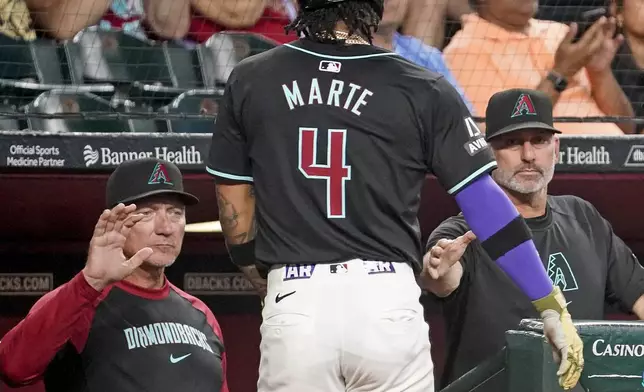Arizona Diamondbacks' Ketel Marte (4) is greeted by bench coach Jeff Banister, left, and head coach Torey Lovullo, right, after scoring a run during the fourth inning of a baseball game against the Oakland Athletics, Sunday, June 30, 2024, in Phoenix. (AP Photo/Darryl Webb)