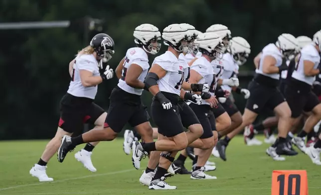 Atlanta Falcons offensive tackle Jake Matthews (70) and the rest of the offensive linemen run during an NFL training camp football practice Thursday, July 25, 2024, in Flowery Branch, Ga. (AP Photo/John Bazemore)