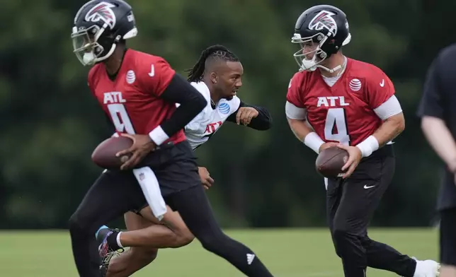 Atlanta Falcons quarterback Michael Penix Jr. (9) running back Bijan Robinson (7) and quarterback Taylor Heinicke (4) run a drill during an NFL training camp football practice Thursday, July 25, 2024, in Flowery Branch, Ga. (AP Photo/John Bazemore)