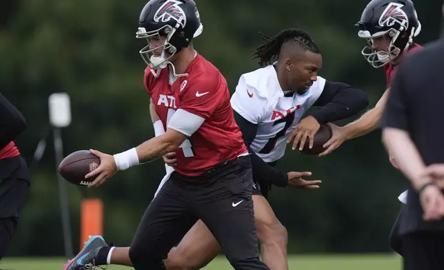 Atlanta Falcons quarterback Taylor Heinicke (4) and running back Bijan Robinson, right, run drills during an NFL training camp football practice Thursday, July 25, 2024, in Flowery Branch, Ga. (AP Photo/John Bazemore)