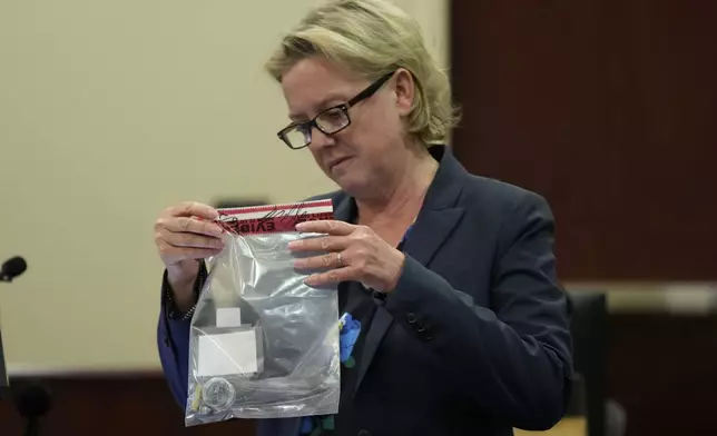 Special prosecutor Kari Morrissey holds an evidence bag with a bullet in it during actor Alec Baldwin's hearing in Santa Fe County District Court, Wednesday, July 10, 2024, in Santa Fe, N.M. Baldwin is facing a single charge of involuntary manslaughter in the death of a cinematographer. (AP Photo/Ross D. Franklin, Pool)