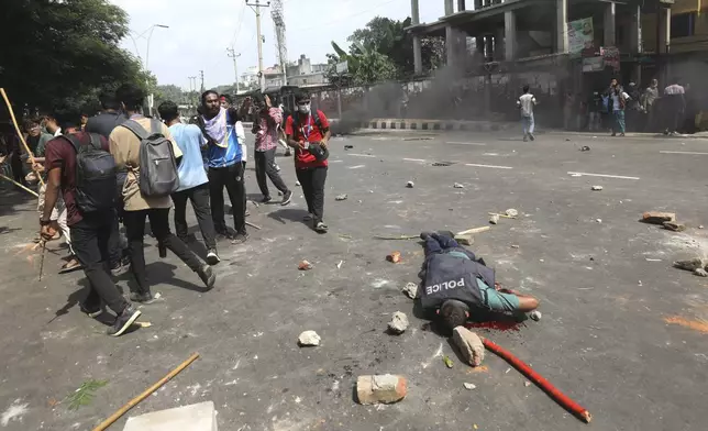 An injured policeman lies on a street during clashes with students protesting against the quota system in public service in Dhaka, Bangladesh, Thursday, July 18, 2024. (AP Photo/Rajib Dhar)