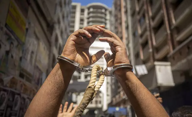 A handcuffed prisoner's hands are raised as he is taken to a court in Dhaka, Bangladesh, Thursday, July 25, 2024. Media reports say that several people have been arrested in recent days across the country after more than a week of chaos triggered by student protests over a quota system in government jobs. (AP Photo/Rajib Dhar)