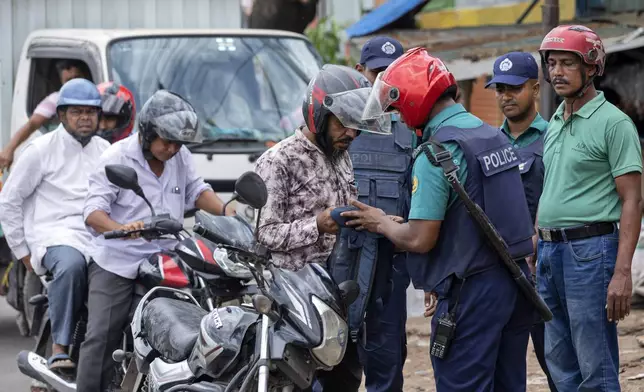 Police inspect a biker's bag on the fourth day of curfew imposed by the government amidst the countrywide deadly clashes, in Dhaka, Bangladesh, Tuesday, July 23, 2024. Internet and mobile data services are still down despite apparent calm in Bangladesh following a verdict that scaled back a controversial quota system for government jobs after weeks of relentless protests that turned deadly. (AP Photo/Rajib Dhar)