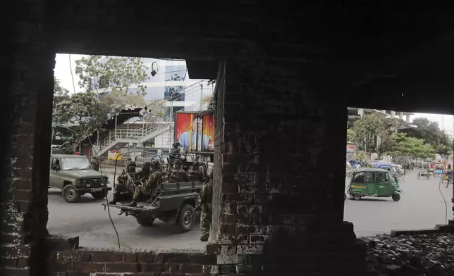 Bangladeshi army patrols in an armored vehicle as seen through a damaged police booth on the fourth day of curfew imposed by the government amidst the countrywide deadly clashes, in Dhaka, Bangladesh, Tuesday, July 23, 2024. Internet and mobile data services are still down despite apparent calm in Bangladesh following a verdict that scaled back a controversial quota system for government jobs after weeks of relentless protests that turned deadly. (AP Photo/Anik Rahman)