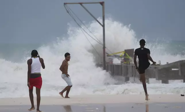 Youths take photos as Hurricane Beryl passes through Bridgetown, Barbados, Monday, July 1, 2024. (AP Photo/Ricardo Mazalan)